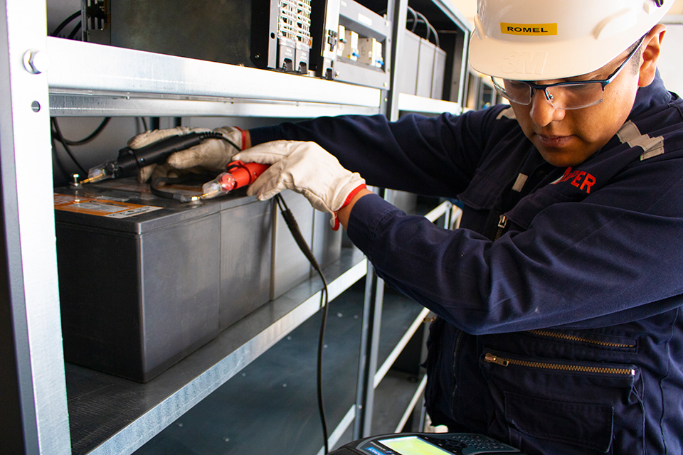Maintenance technician measuring voltage on lead acid battery